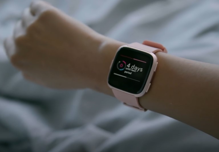 A light pink smartwatch displays a countdown to the next menstrual cycle