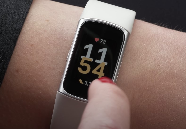 A close-up view of a fitness tracker displaying the time at 11:54